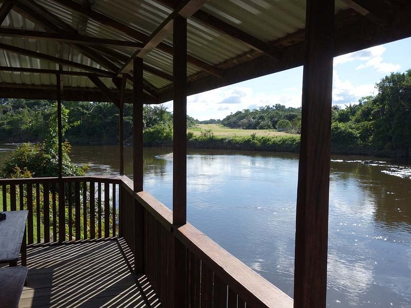 Uitzicht vanaf een houten veranda op een rustige rivier en omringende natuur
